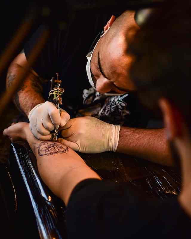 Tatuador aplicando tatuagem detalhada no estúdio Art Brilho Ink no Tatuapé