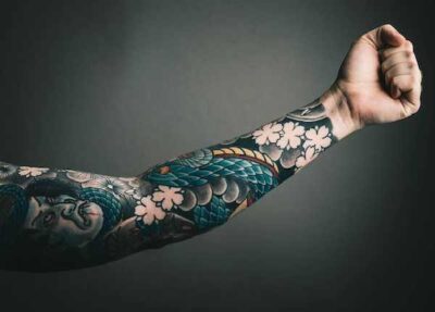 Homem recebendo uma tattoo no braço dentro de estúdio de tatuagem no Tatuapé com iluminação profissional e tatuador experiente.