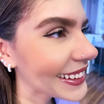 Close-up de um nariz feminino com um piercing delicado e brilhante aplicado na lateral.
