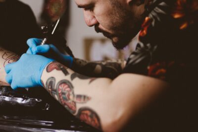 Tatuagem no braço feita com precisão por tatuador em São Paulo Pessoa recebendo tatuagem no braço em estúdio profissional em São Paulo, com artista utilizando equipamento esterilizado.