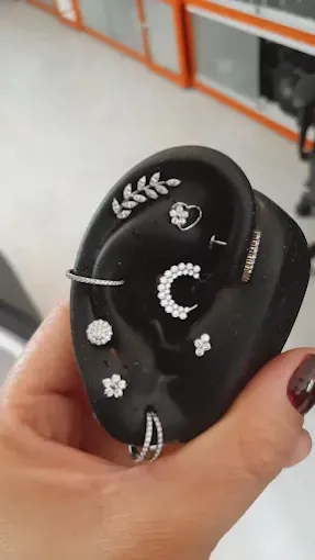 Profissional aplicando piercing em cliente no estúdio de piercing no Tatuapé com ambiente higienizado.